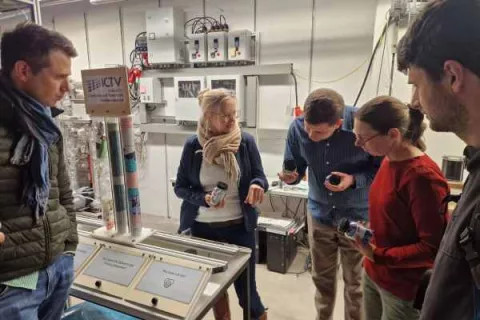 Gruppe von Fachleuten untersucht Geräte während einer praxisnahen Schulung zur Ökobilanzierung in einer Laborumgebung.